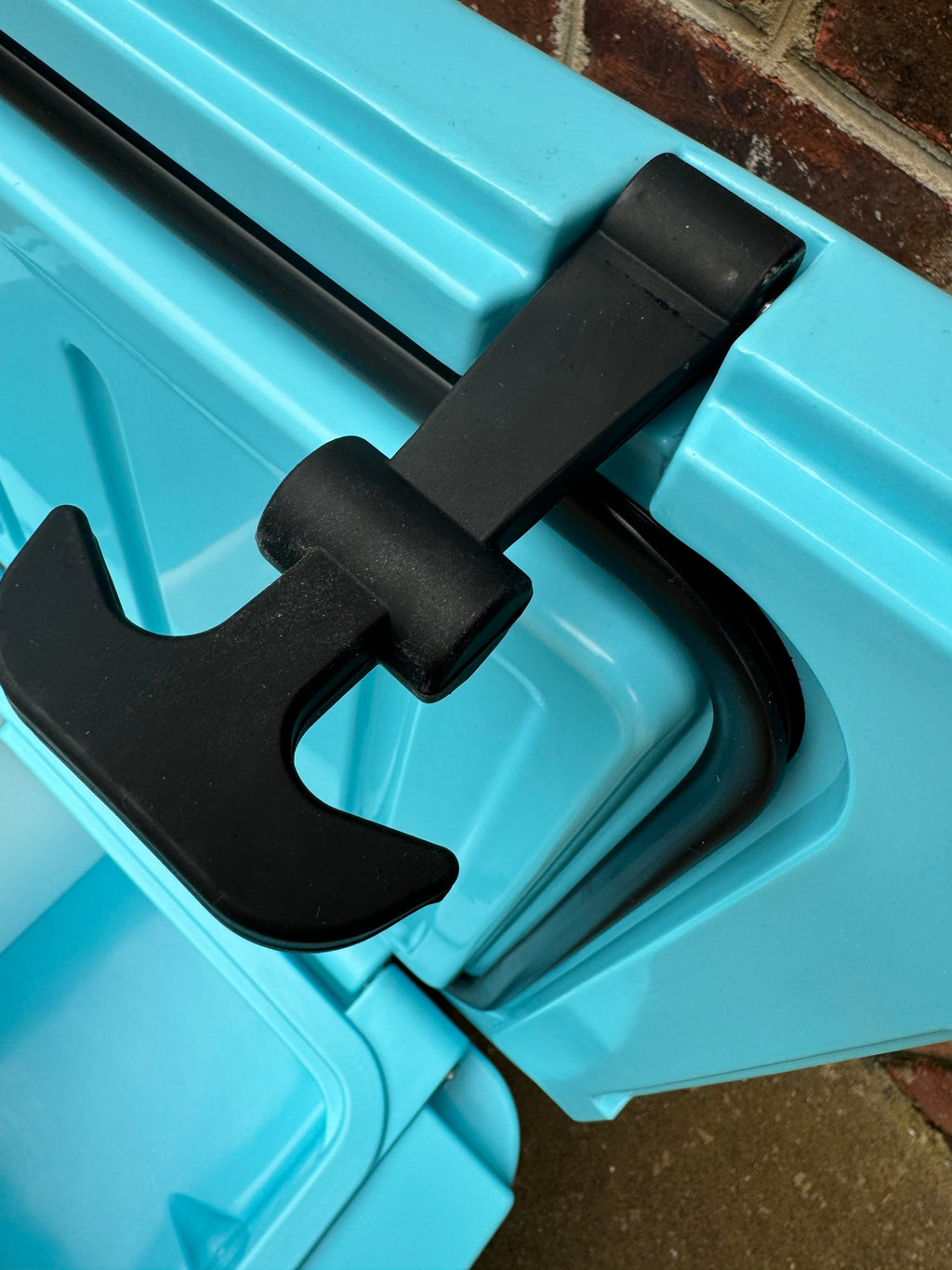 Close-up of a blue storage container with a black handle on a brick surface.