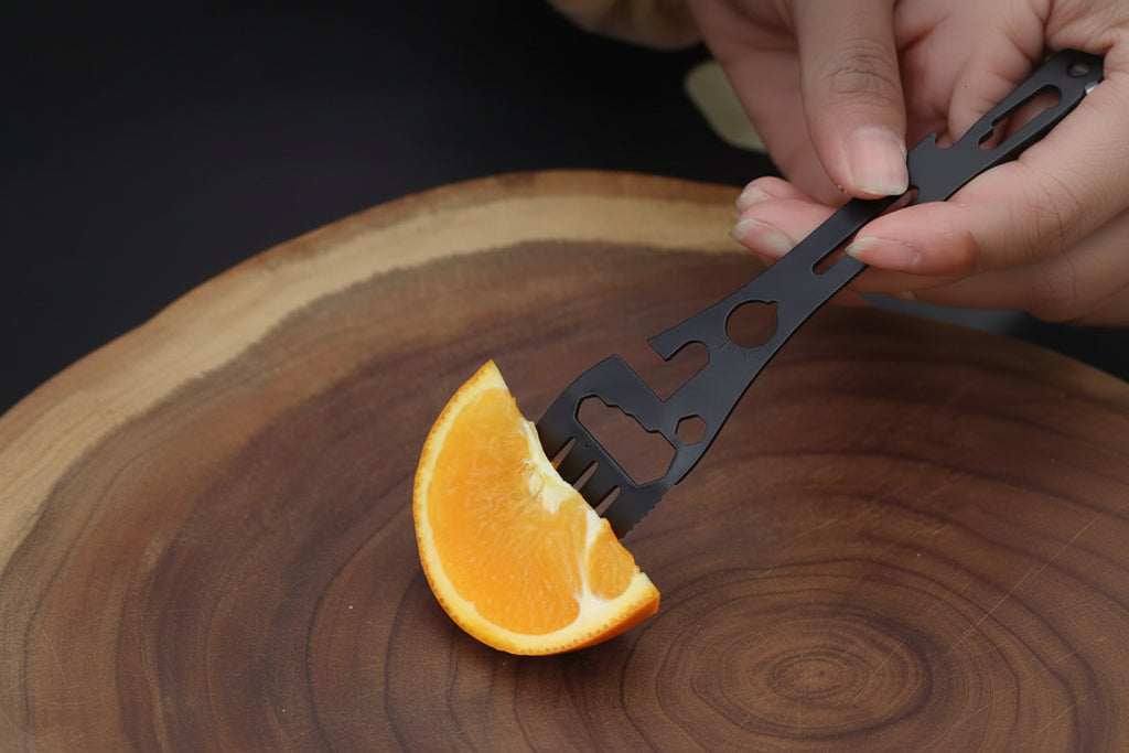 Person using a black tool to feed an orange slice on a wooden surface with text overlay.
