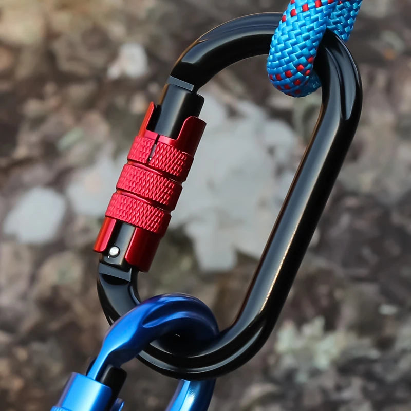Close-up of a carabiner with a red lock mechanism against a blurred natural background - offered by the best hiking and climbing gear store in New York, The Adirondack Tool Company