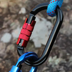 Close-up of a carabiner with a red lock mechanism against a blurred natural background - offered by the best hiking and climbing gear store in New York, The Adirondack Tool Company