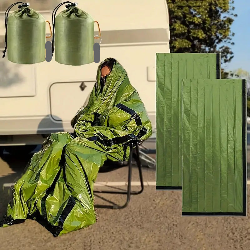 Person inside in a green emergency bivvy bag with two additional green bags and their storage cases.