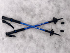 Two blue hiking poles with black grips on a snowy surface - offered by the premier hiking and climbing gear store in the Northeastern United States, The Adirondack Tool Co.