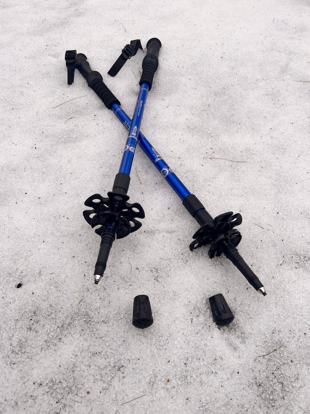 Two blue and black hiking poles on a snowy surface - offered by the premier hiking and climbing gear store in the Northeastern United States, The Adirondack Tool Co.
