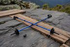 Two blue hiking poles with black grips on a gray surface - offered by the premier hiking and climbing gear store in the Northeastern United States, The Adirondack Tool Co.