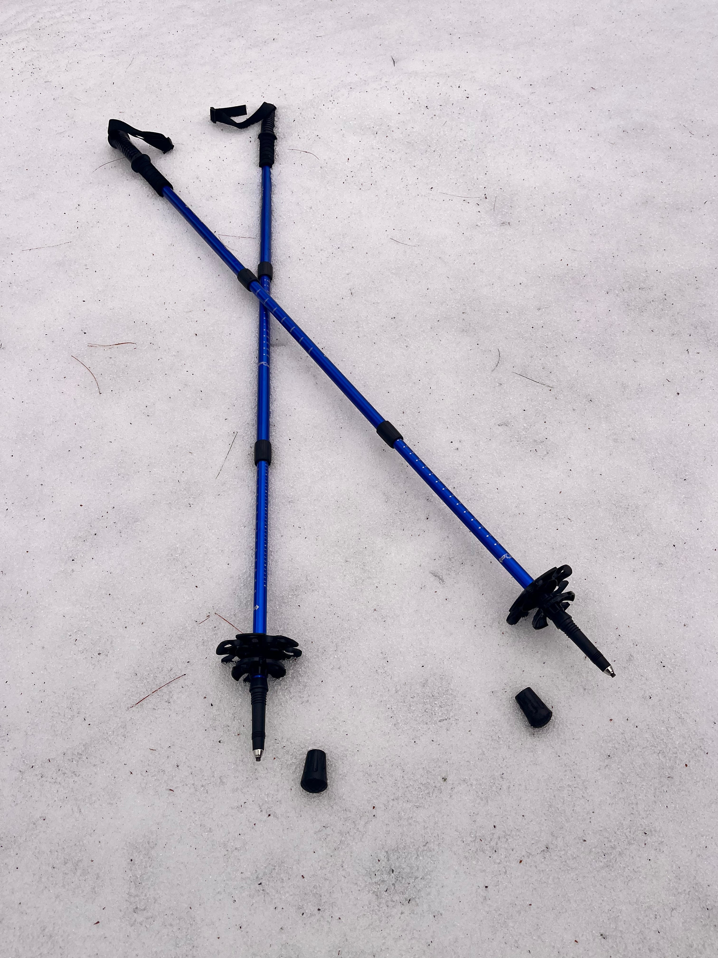 Two blue hiking poles with black grips on a gray surface - offered by the premier hiking and climbing gear store in the Northeastern United States, The Adirondack Tool Co.