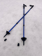 Two blue hiking poles with black grips on a light gray surface - offered by the premier hiking and climbing gear store in the Northeastern United States, The Adirondack Tool Co.
