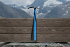 Blue ice axe with black strap on a white background