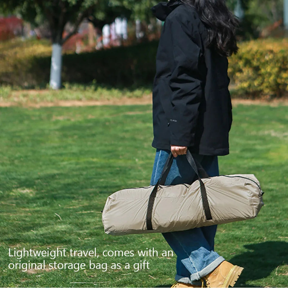Person holding The Adirondack Tool Co.'s pop-up camping tent with its included storage bag in a park