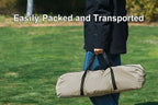 Person holding The Adirondack Tool Co.'s pop-up camping tent with its included storage bag in a park
