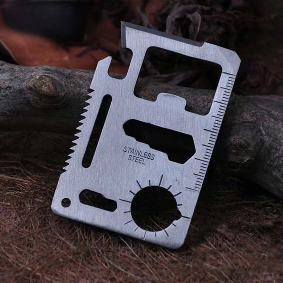 Stainless steel multitool card with various tools on a forest floor