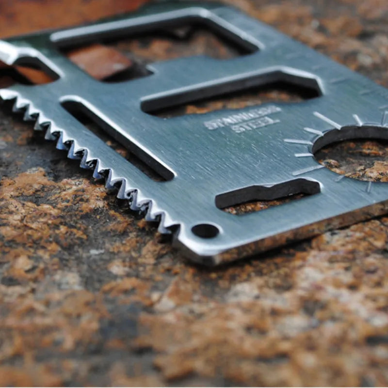 Stainless steel multitool card with various tools on a textured surface
