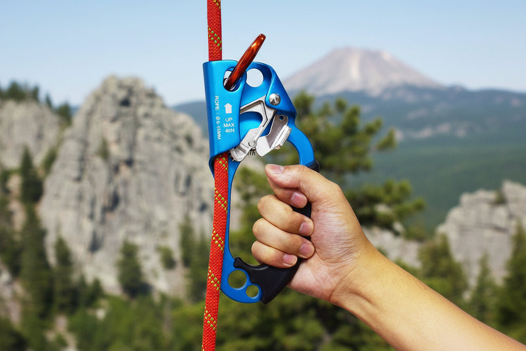 Hand holding a blue ascender climbing device with red rope on a white background - offered by the best climbing gear store in New York, The Adirondack Tool Co.
