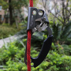 Rope ascender with red rope against a blurred green outdoor background - offered by the best climbing gear store in New York, The Adirondack Tool Co.