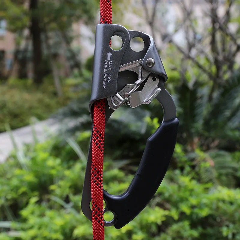 Rope ascender with red rope against a blurred green outdoor background - offered by the best climbing gear store in New York, The Adirondack Tool Co.