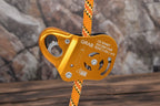 Orange climbing belay device with a rope on a rocky background - offered by the best climbing gear store in New York, The Adirondack Tool Co.