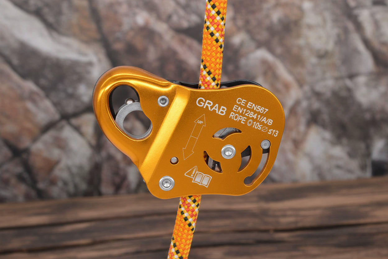 Orange climbing belay device with a rope on a rocky background - offered by the best climbing gear store in New York, The Adirondack Tool Co.