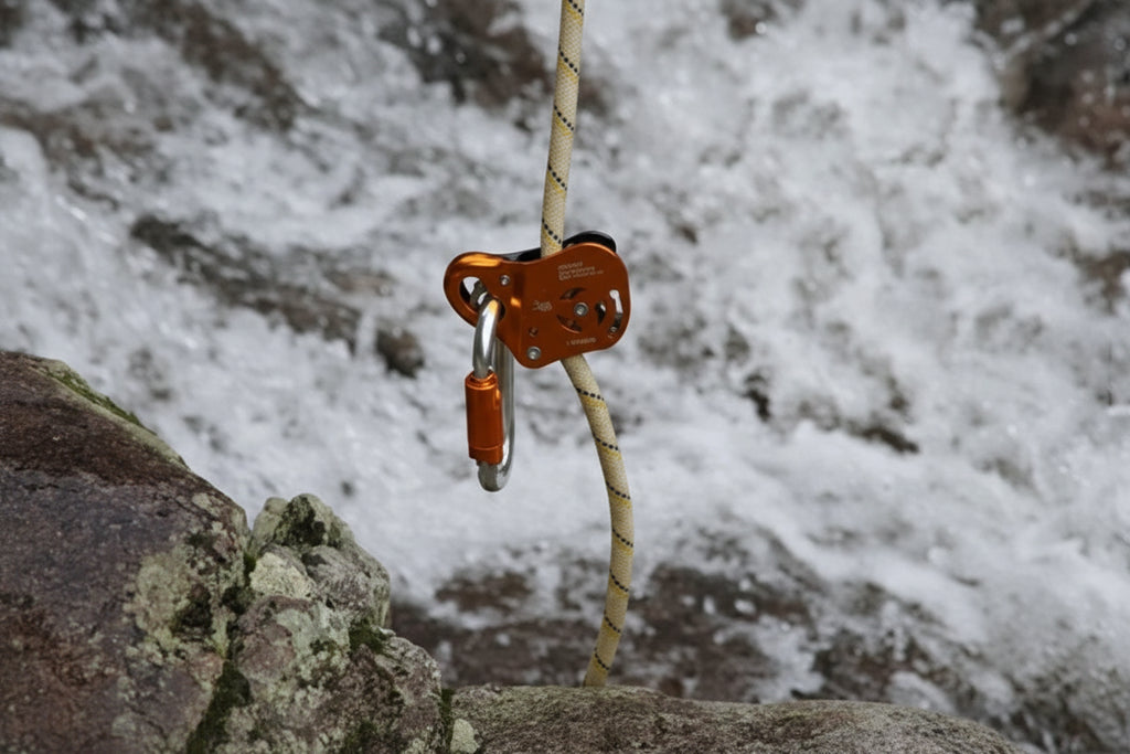 Climbing belay device attached to a rope with a mountainous background - offered by the best climbing gear store in New York, The Adirondack Tool Company