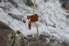 Climbing belay device attached to a rope with a mountainous background - offered by the best climbing gear store in New York, The Adirondack Tool Company