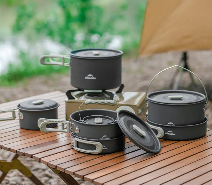 Set of camping cookware on a wooden table with a natural outdoor background - offered by the best camping gear store in New York, The Adirondack Tool Company