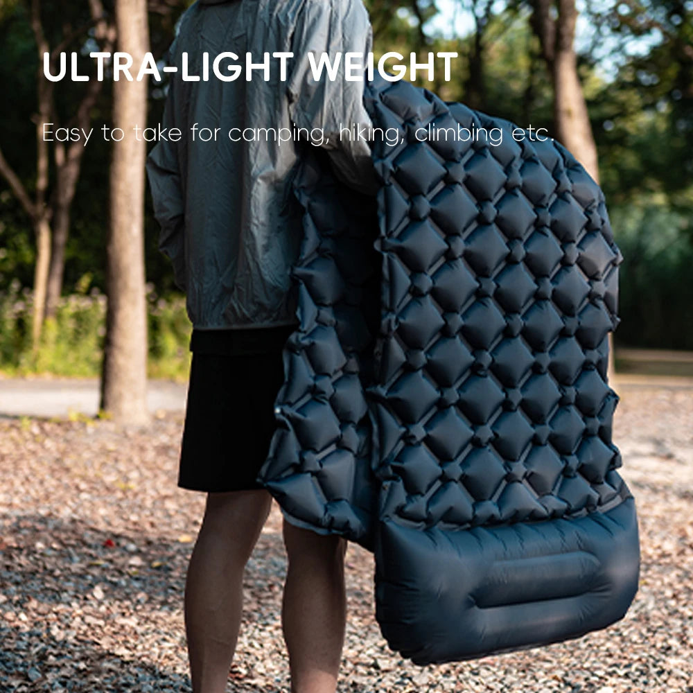 Person holding an ultra-light inflatable camping mat from The Adirondack Tool Co. in a natural setting