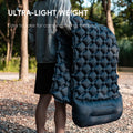 Person holding an ultra-light inflatable camping mat from The Adirondack Tool Co. in a natural setting