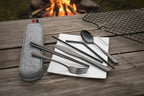 Black camping cutlery set with carrying case on a wooden surface - offered by the best camping and hiking gear store in the United States, The Adirondack Tool Co.
