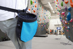 Blue and black chalk bag worn on a person's waist against a camouflage background - offered by the best hiking and climbing gear store in New Hampshire, The Adirondack Tool Co.