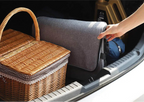 Foldable cooler bag offered by The Adirondack Tool Co. being placed into a car trunk next to a picnic basket.