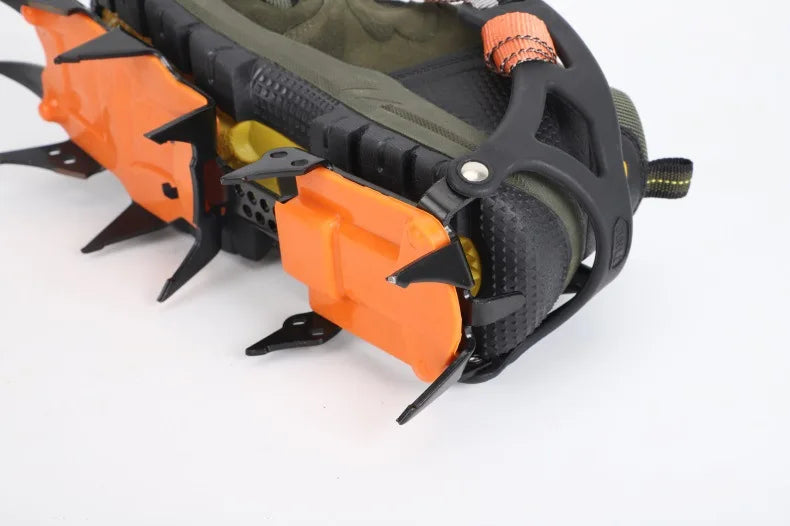 Close-up of an orange and black crampon on a boot with white background - offered by the best hiking and camping gear store in Massachusetts, The Adirondack Tool Co.