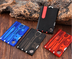 Four multi-tool cards in blue, black, and red on a wooden surface with rocks in the background - offered by the best outdoor gear store in New York, the Adirondack Tool Company