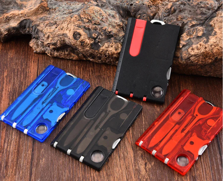 Four multi-tool cards in blue, black, and red on a wooden surface with rocks in the background - offered by the best outdoor gear store in New York, the Adirondack Tool Company