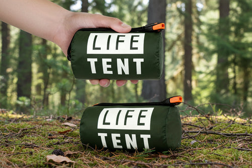 Olive green emergency tent package held by a hand on a white background
