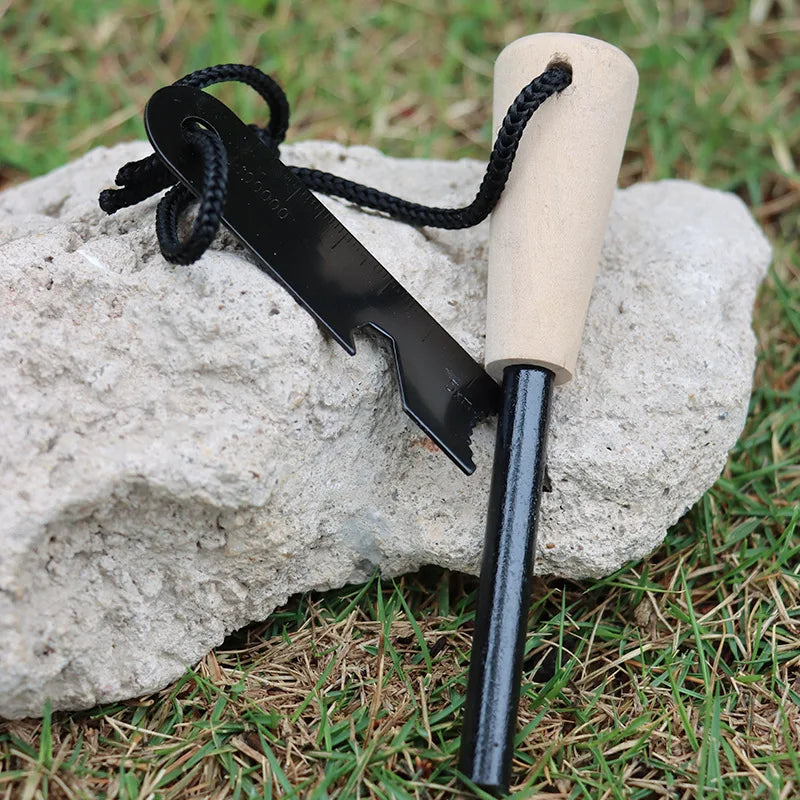 Fire starter tool with wooden handle and metal striker on a rock - offered by the best camping gear store in New York, The Adirondack Tool Co.