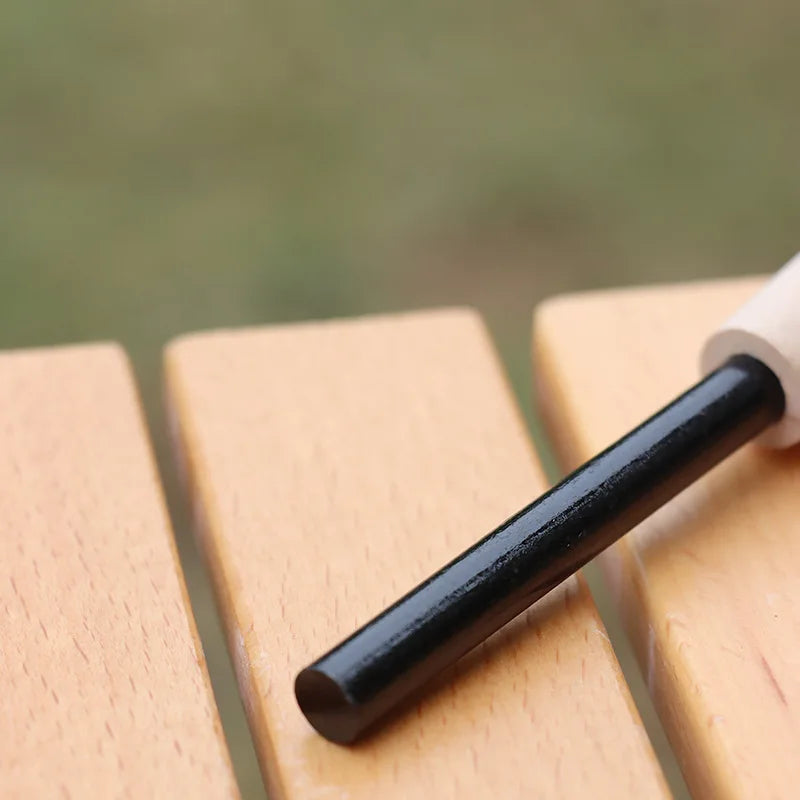 Black magnesium bar on a wooden surface with a blurred green background - offered by the best camping gear store in New York, The Adirondack Tool Co.