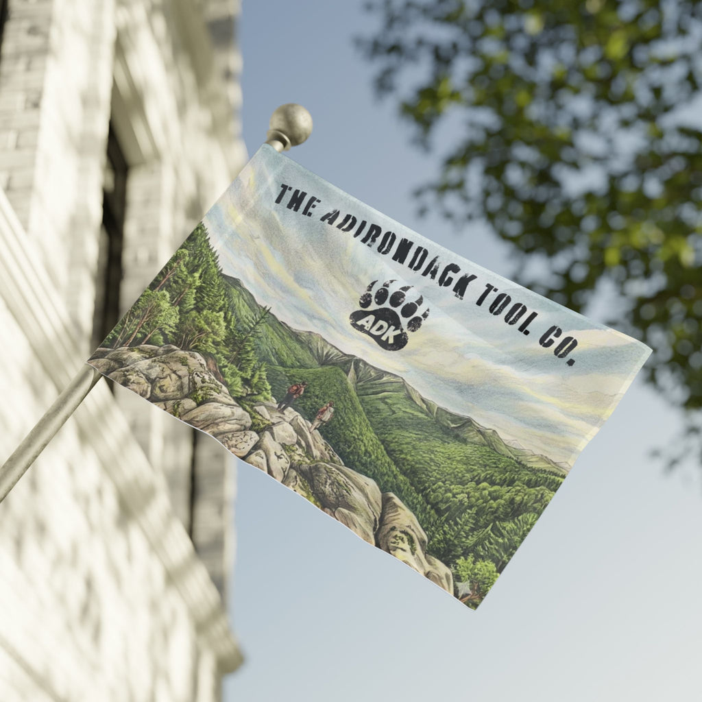 Flag with scenic design and 'The Adirondack Tool Co.' branding on a building