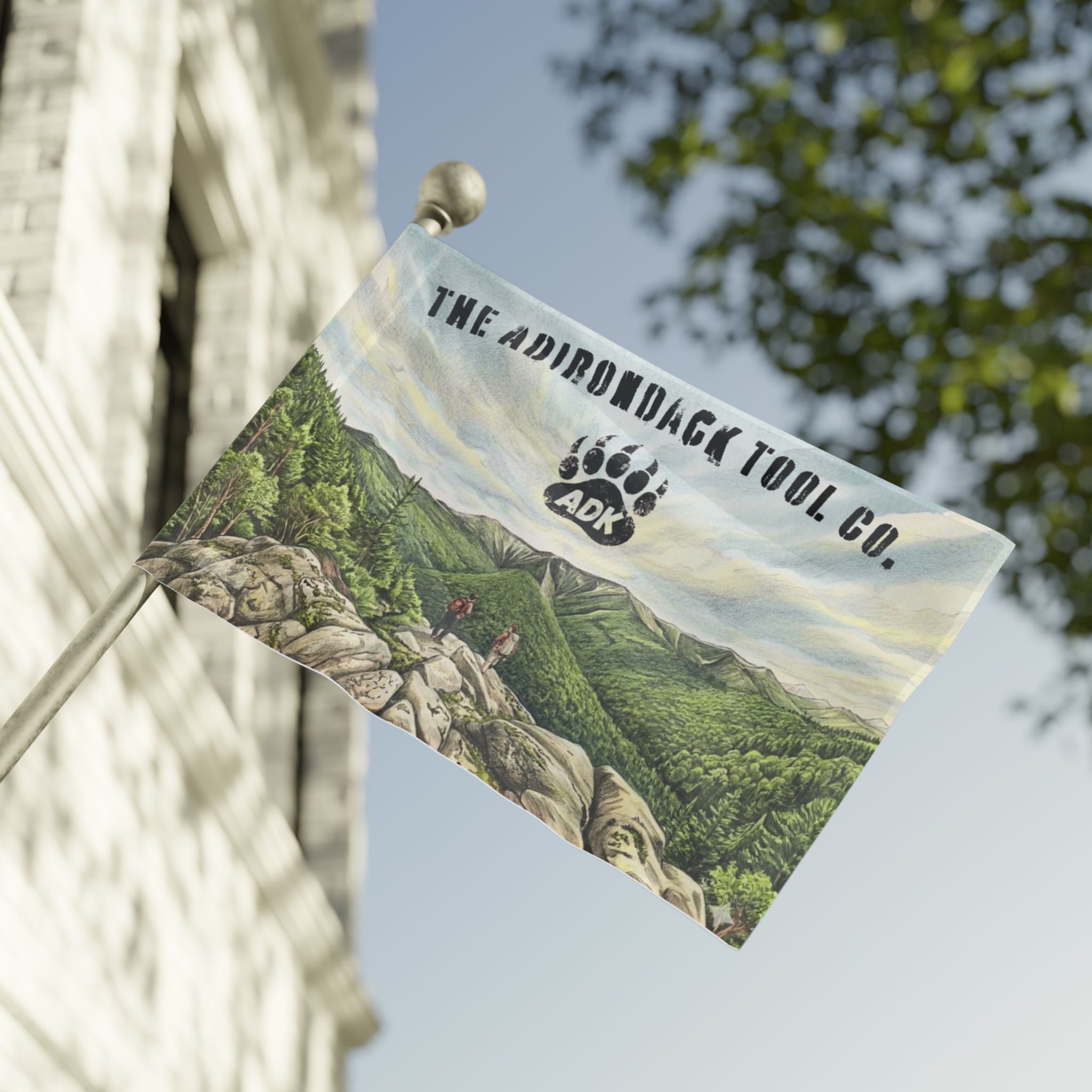 Flag with scenic design and 'The Adirondack Tool Co.' branding on a building