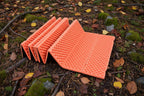 Foldable orange sleeping / sitting mat from The Adirondack Tool Co. on a white background.