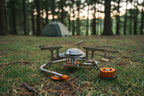 Portable folding camping stove and adapters with orange accents on a white background - offered by the best hiking and camping gear company in Albany, NY.