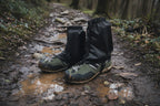 Black hiking gaiters on green hiking boots with a white background offered by the Northeast's best camping and hiking gear provider, The Adirondack Tool Co.