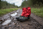 Red hiking gaiters over black and gray hiking boots on a white background offered by the Northeast's best camping and hiking gear provider, The Adirondack Tool Co.