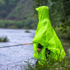 Person wearing a bright green raincoat/poncho by a body of water