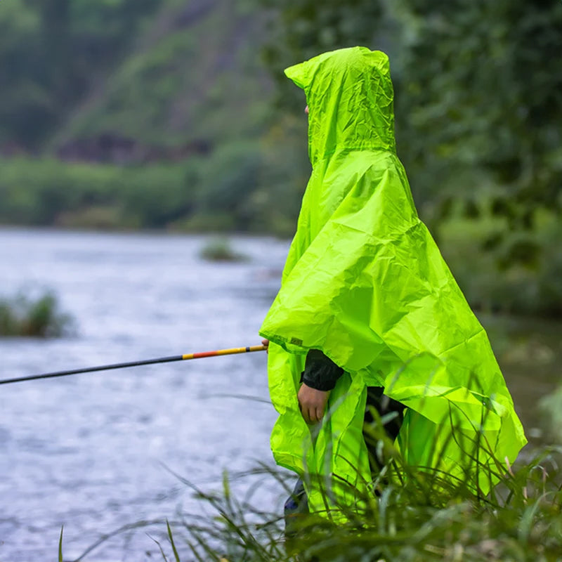 Person wearing a bright green raincoat/poncho by a body of water