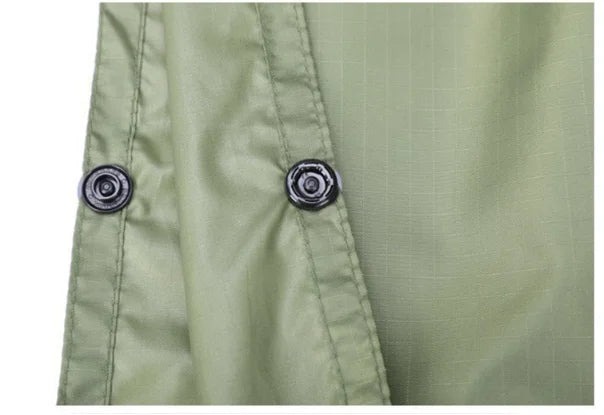 Close-up of green poncho fabric with two buttons on a white background - offered by the best hiking gear store in New York, The Adirondack Tool Co.