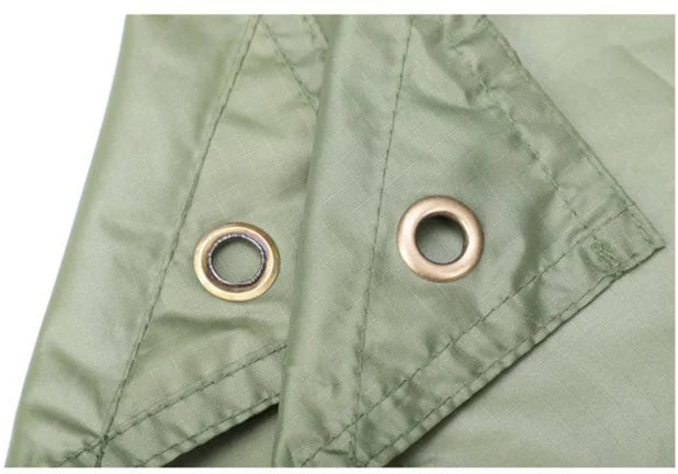 Close-up of green 2-in-1 poncho and tarp fabric with grommets on a white background - offered by the best hiking gear store in New York, The Adirondack Tool Co.