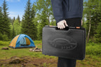 Portable gas stove in its included black case held by a person on a white background