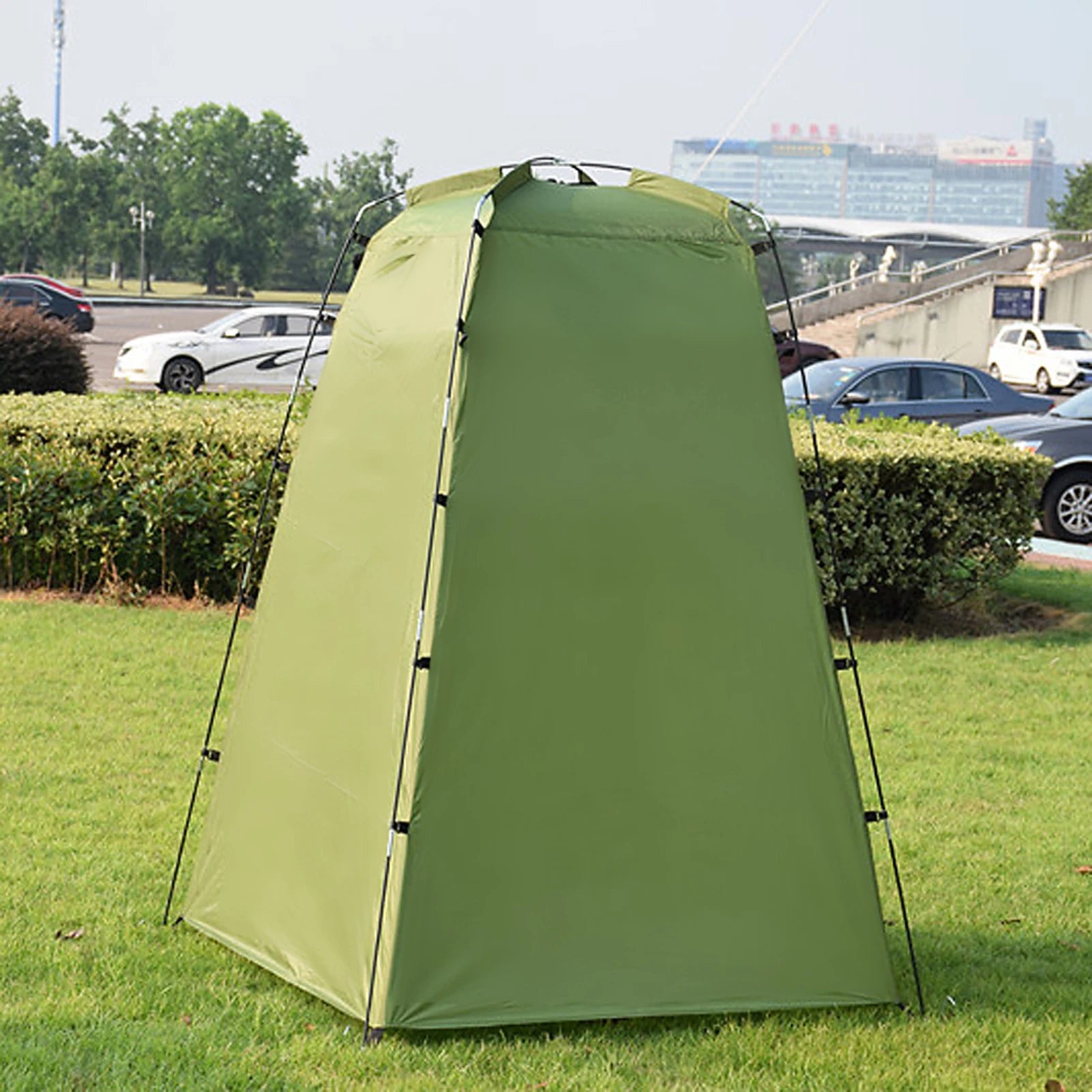 Green privacy tent with black poles and straps with cars in the background - offered by the best outdoor gear company in New York, The Adirondack Tool Co.