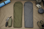 Two sleeping bags, one olive green and one gray. The olive green sleeping bag is shown with its included carrying case - offered by the best camping gear store in New York, The Adirondack Tool Company