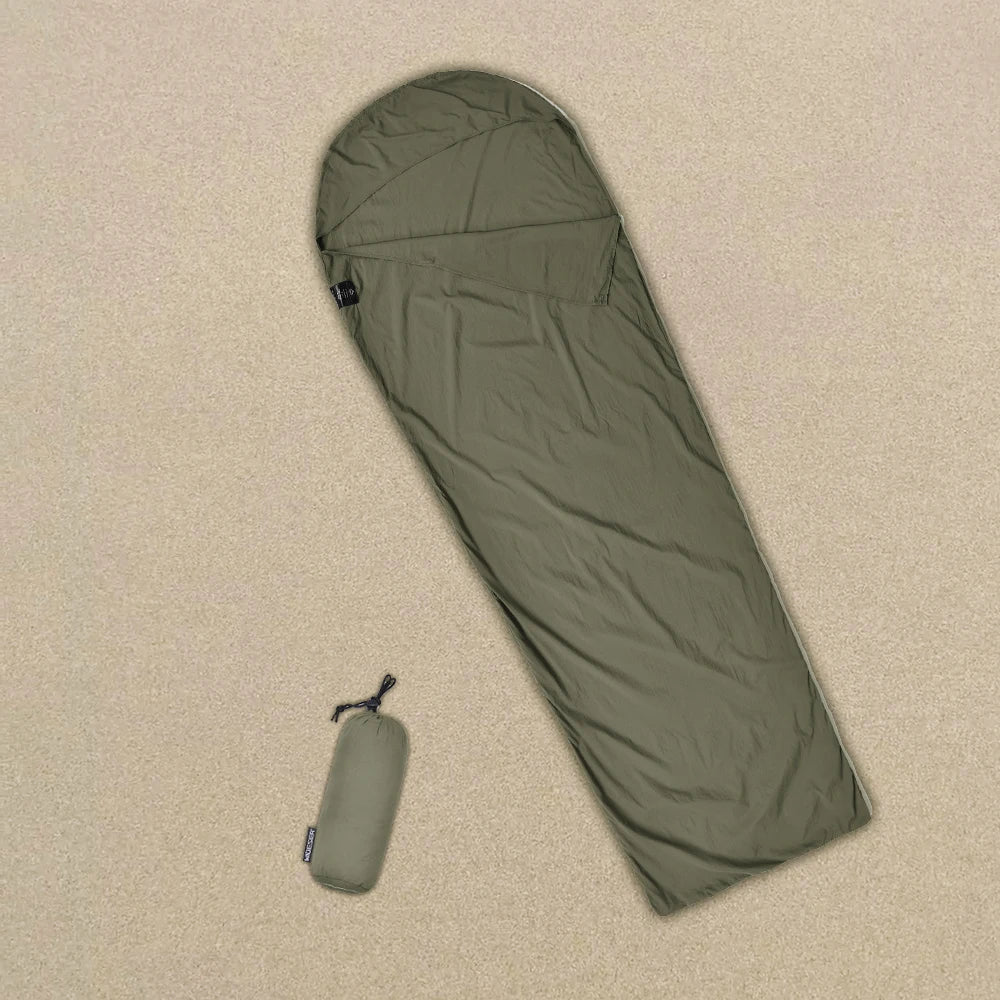 Green sleeping bag on a beige carpet