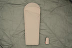 Beige sleeping bag with a matching carrying bag on a tent floor background - offered by the best camping gear store in New York, The Adirondack Tool Co.