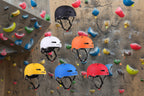6 sports helmets on a rock climbing background - offered by the best outdoor sports gear store in Massachusetts, The Adirondack Tool Co.
